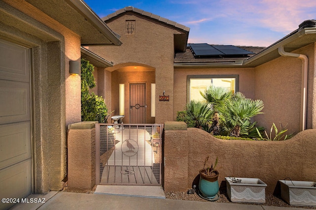 exterior entry at dusk featuring a garage and solar panels