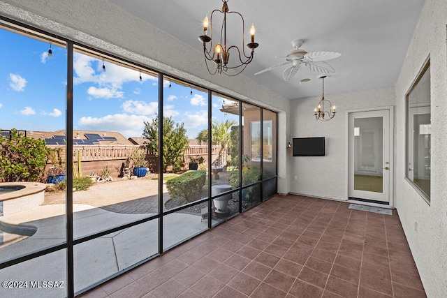 unfurnished sunroom featuring ceiling fan with notable chandelier