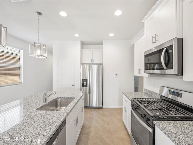 kitchen featuring white cabinets, stainless steel appliances, light stone counters, and a sink