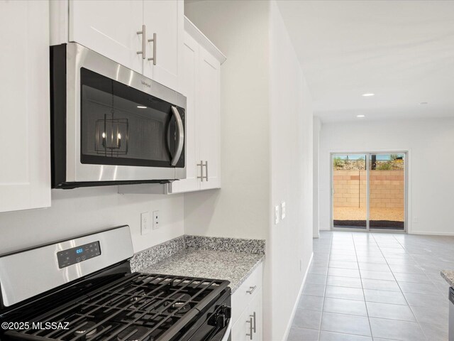 kitchen with light tile patterned floors, appliances with stainless steel finishes, baseboards, and white cabinetry