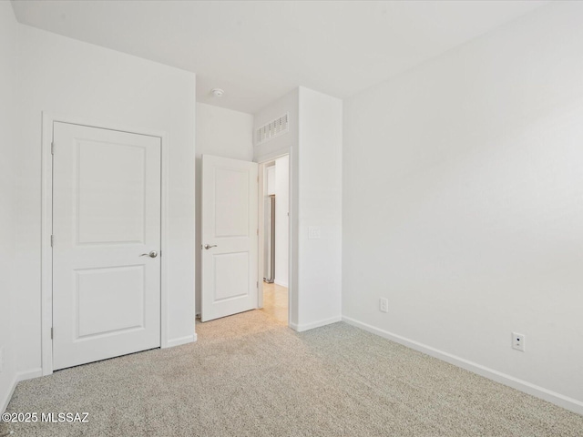 unfurnished bedroom with baseboards, visible vents, and carpet