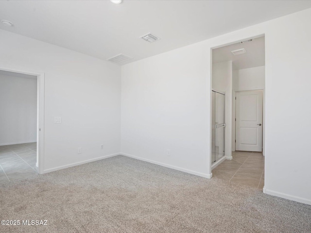 carpeted spare room with baseboards, visible vents, and tile patterned flooring