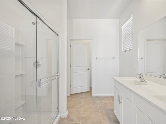 bathroom with double vanity, a sink, a stall shower, and tile patterned flooring