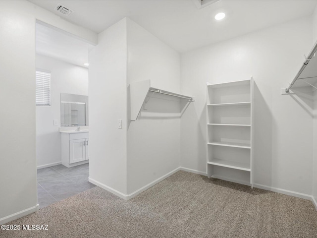 walk in closet with carpet floors, visible vents, and a sink