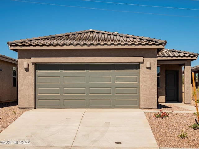 mediterranean / spanish-style house featuring a garage, a tiled roof, concrete driveway, and stucco siding