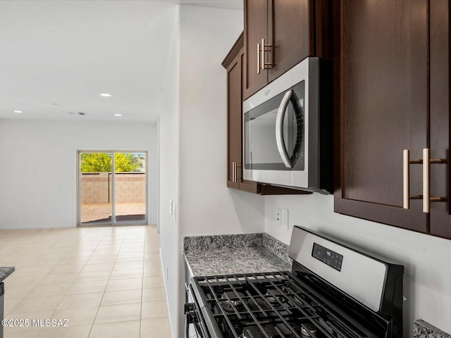 kitchen with dark brown cabinetry, appliances with stainless steel finishes, light stone counters, recessed lighting, and light tile patterned floors