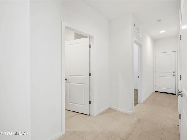 hall featuring baseboards, light tile patterned flooring, and visible vents