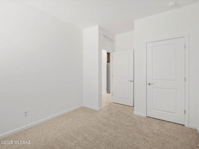spare room featuring baseboards, visible vents, and light colored carpet
