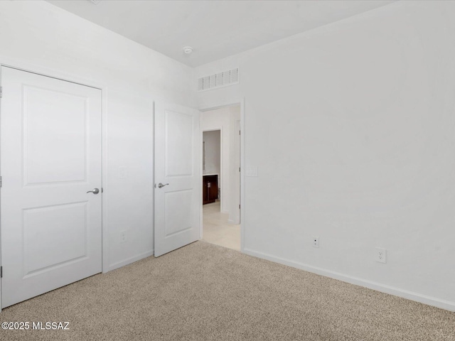 unfurnished bedroom with carpet flooring, baseboards, and visible vents