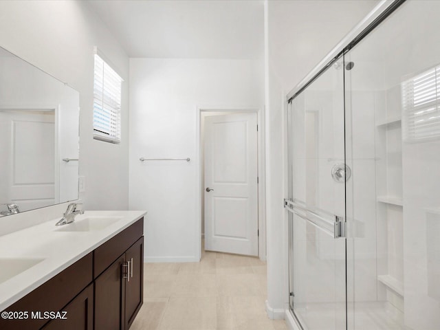 bathroom with a sink, baseboards, a stall shower, and double vanity