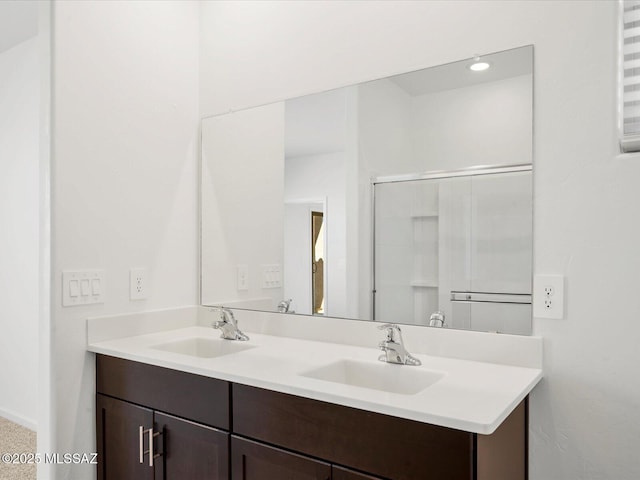 bathroom with double vanity, a sink, and a shower with door