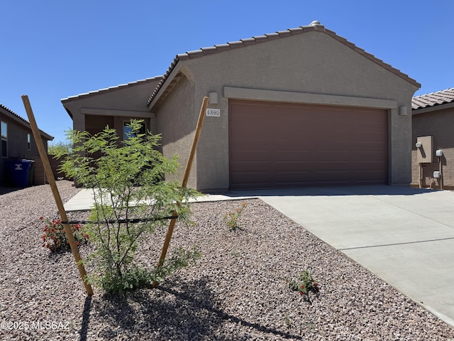 ranch-style home featuring an attached garage, stucco siding, a tile roof, and concrete driveway
