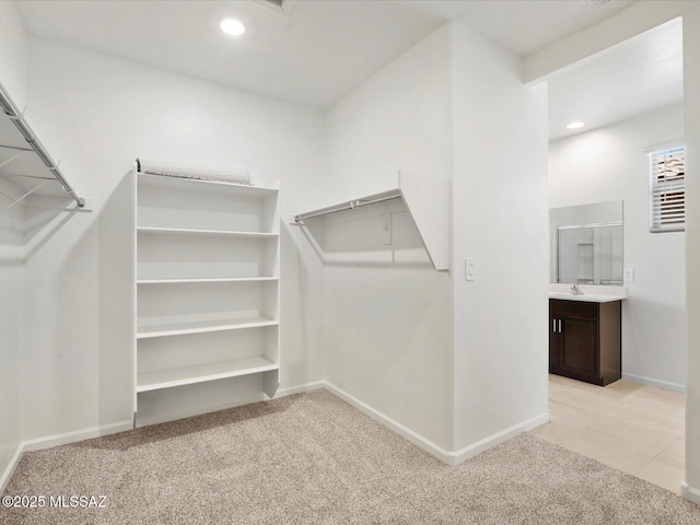 walk in closet with light colored carpet and a sink