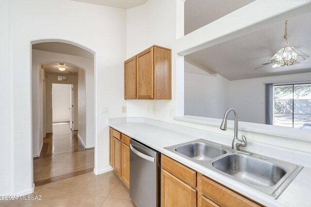 kitchen with pendant lighting, a notable chandelier, stainless steel dishwasher, sink, and light tile patterned flooring