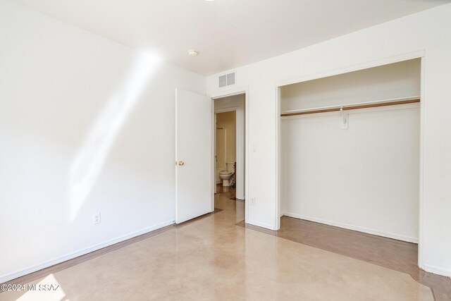 unfurnished bedroom with concrete floors and a closet