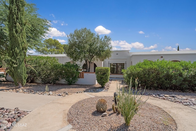 pueblo-style home with a fenced front yard and stucco siding