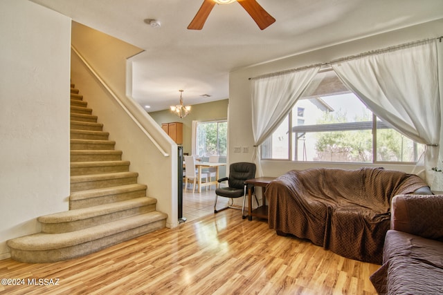 living room featuring light hardwood / wood-style floors, ceiling fan with notable chandelier, and plenty of natural light