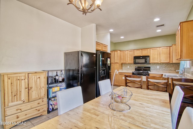 kitchen with light tile patterned flooring, sink, black appliances, backsplash, and an inviting chandelier