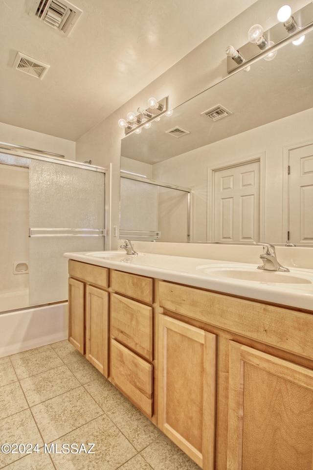 bathroom featuring tile patterned flooring, vanity, and bath / shower combo with glass door