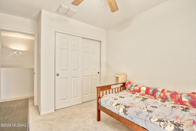 bedroom with ceiling fan, light carpet, and a closet