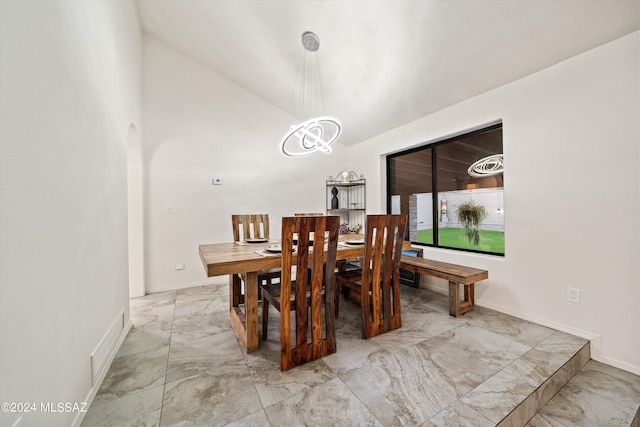 dining area featuring lofted ceiling, marble finish floor, arched walkways, an inviting chandelier, and baseboards