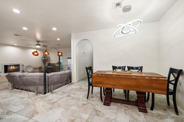 dining room featuring visible vents, ceiling fan, recessed lighting, arched walkways, and a glass covered fireplace