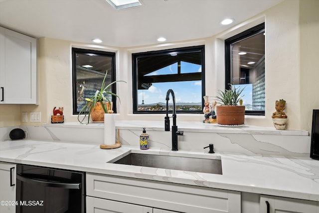 kitchen with dishwasher, light stone counters, sink, and white cabinets