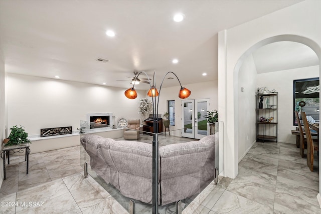 living room featuring visible vents, a lit fireplace, recessed lighting, arched walkways, and marble finish floor
