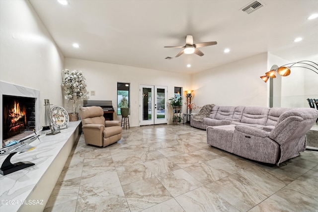 living room with ceiling fan, french doors, and a fireplace