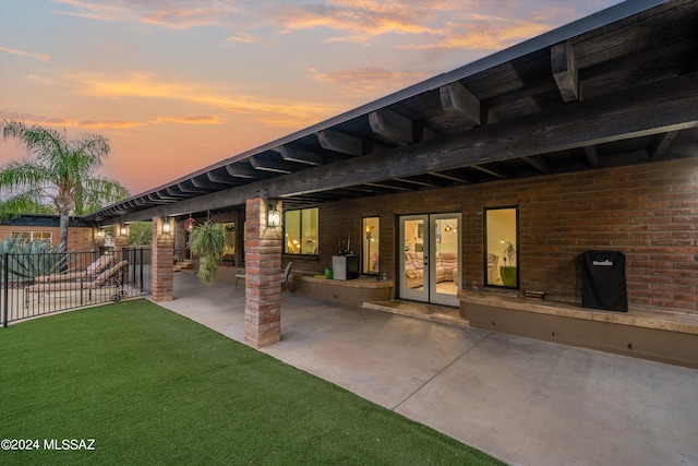 patio terrace at dusk featuring a lawn