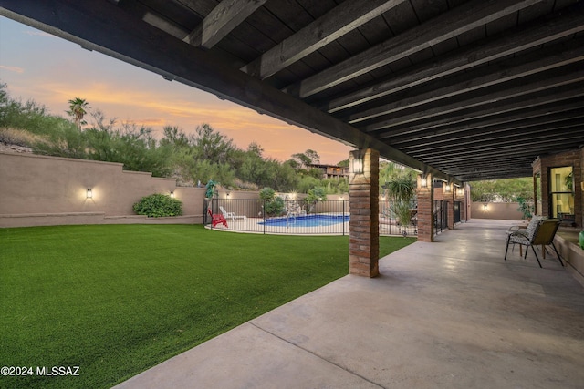 patio terrace at dusk with a fenced in pool and a yard