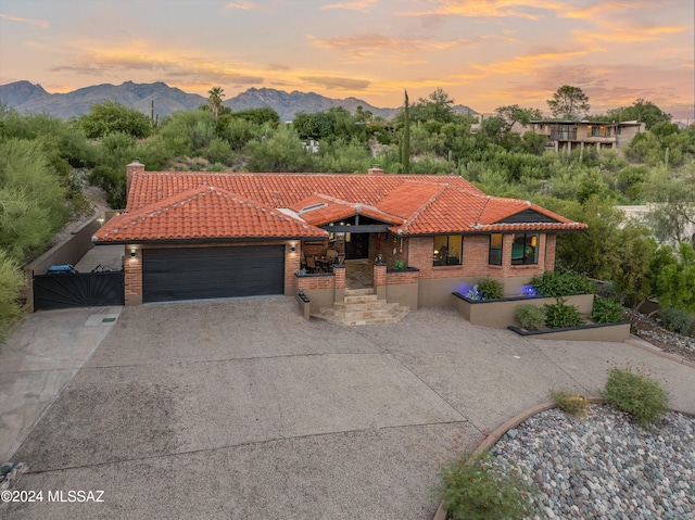 mediterranean / spanish house with concrete driveway, a tiled roof, an attached garage, and a mountain view