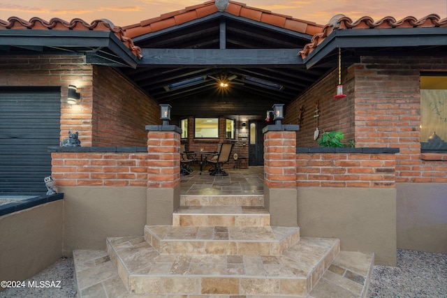 doorway to property with a tile roof and brick siding