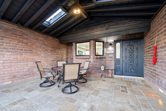 interior space featuring brick wall and lofted ceiling with skylight