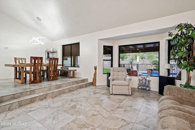 living room featuring a chandelier, marble finish floor, and vaulted ceiling