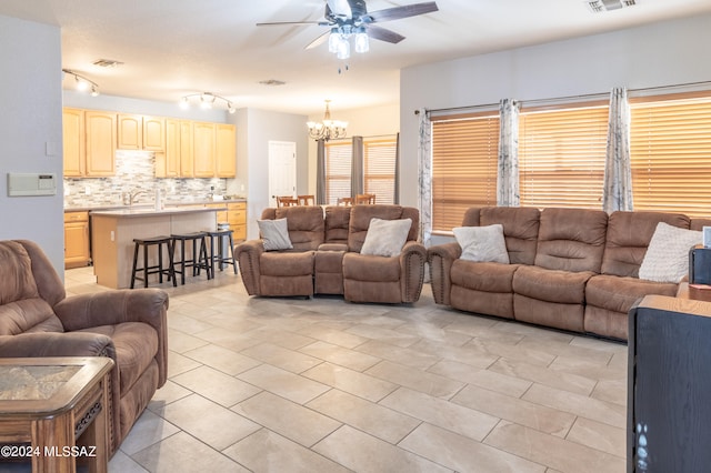 tiled living room featuring ceiling fan with notable chandelier