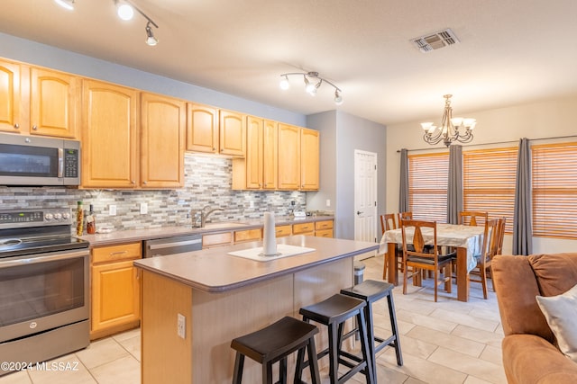 kitchen with tasteful backsplash, a chandelier, a center island, hanging light fixtures, and appliances with stainless steel finishes