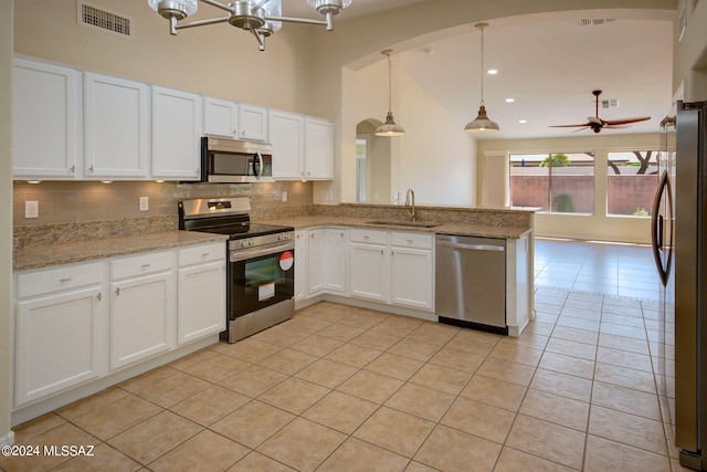 kitchen featuring stainless steel appliances, sink, kitchen peninsula, white cabinetry, and hanging light fixtures