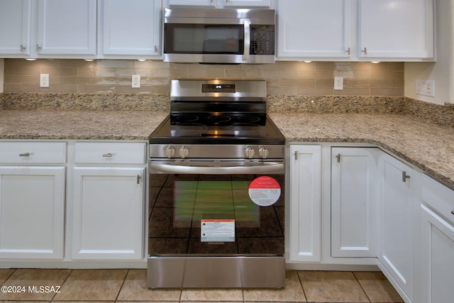 kitchen with appliances with stainless steel finishes, light stone counters, and white cabinets