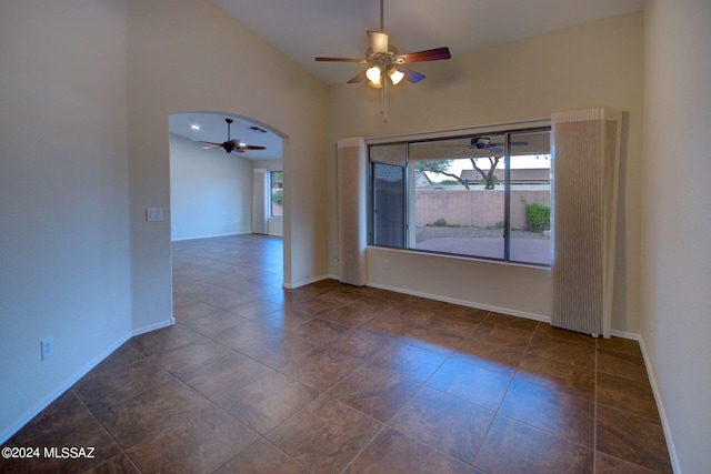 tiled spare room featuring ceiling fan, high vaulted ceiling, and a wealth of natural light