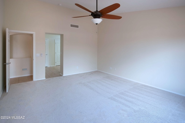 unfurnished bedroom with ceiling fan, a towering ceiling, and light colored carpet