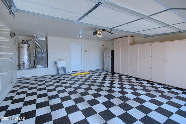 garage with stainless steel refrigerator, a garage door opener, sink, and water heater