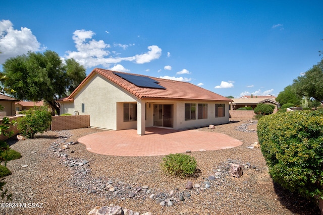 rear view of house featuring solar panels and a patio area