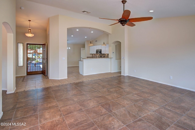 unfurnished living room with dark tile patterned floors, high vaulted ceiling, and ceiling fan