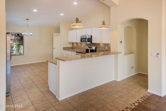 kitchen featuring kitchen peninsula, decorative light fixtures, backsplash, white cabinetry, and stainless steel appliances