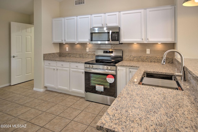 kitchen featuring stainless steel appliances, sink, light stone counters, and white cabinetry