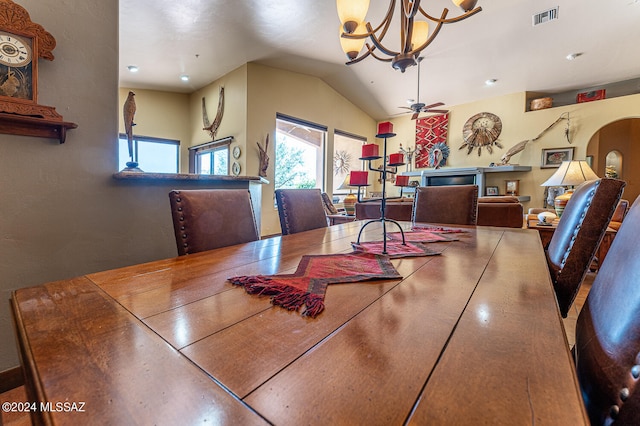 dining space with ceiling fan with notable chandelier and vaulted ceiling