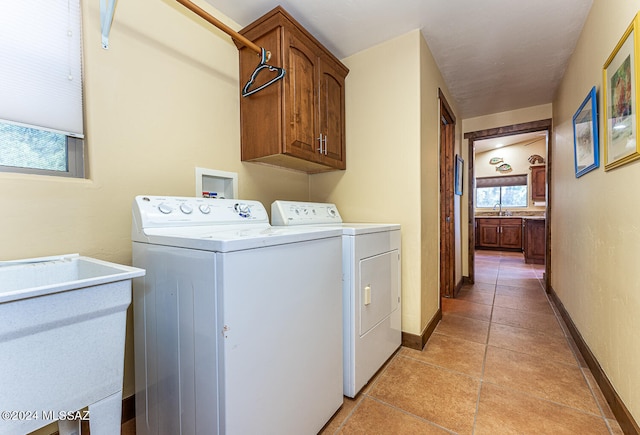 laundry room with light tile patterned floors, independent washer and dryer, cabinets, and sink