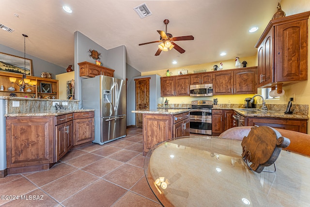 kitchen with pendant lighting, a kitchen island, ceiling fan, appliances with stainless steel finishes, and lofted ceiling