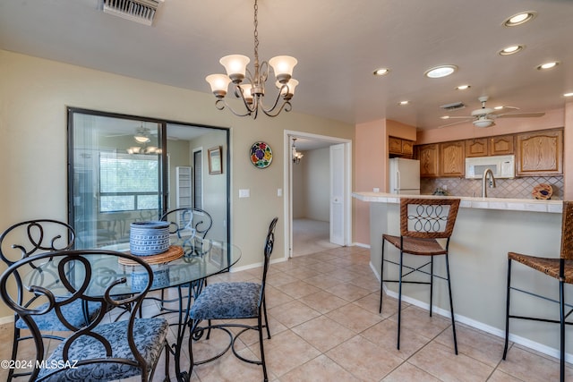 dining space with sink, ceiling fan with notable chandelier, and light tile patterned floors